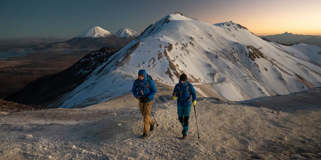 Two climbers on a snowy ridge in the Bolivian Andes at dusk