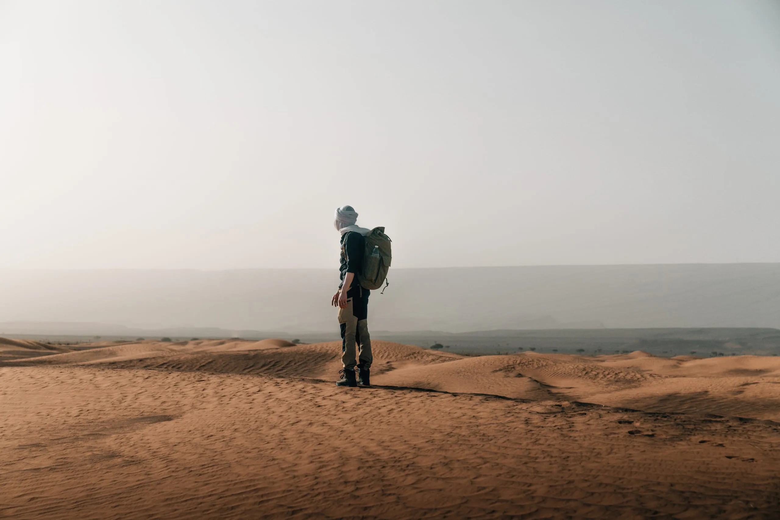 Ein Mann mit Rucksack auf einer Düne in der marokkanischen Sahara